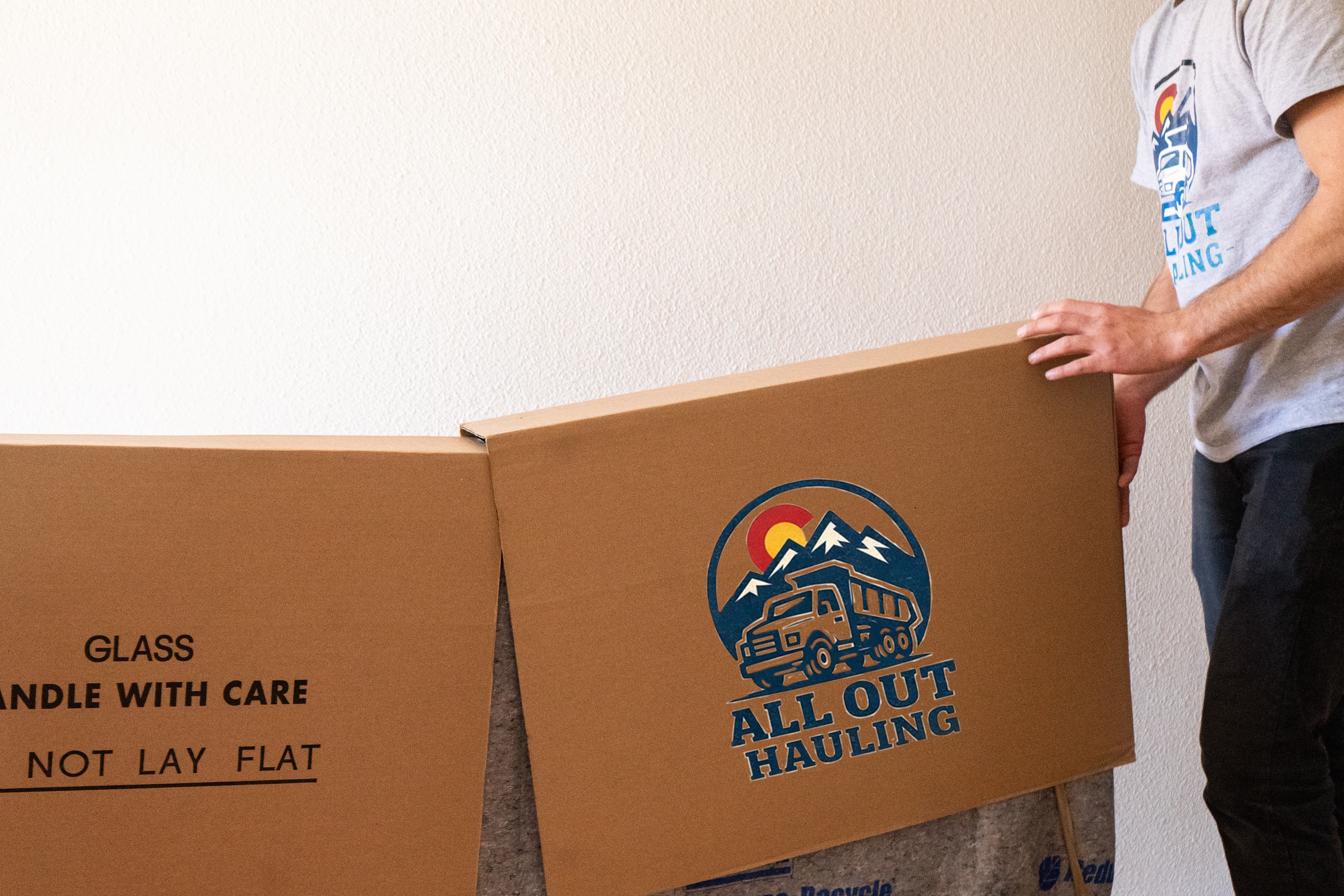 All Out Hauling team moving a large labeled box inside a home